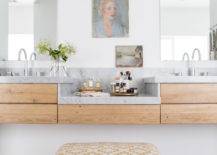 modern art in master bathroom with wood vanities stool to sit on white walls and marble countertops