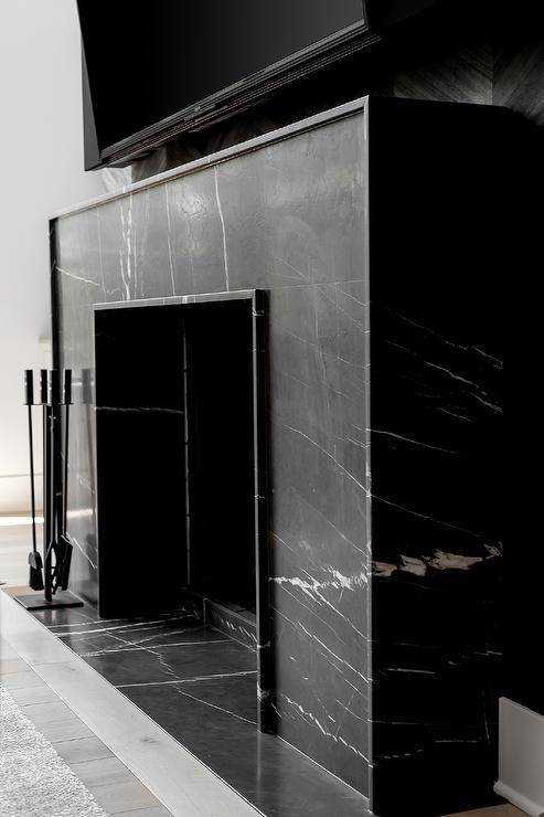 A modern honed marble black fireplace is fixed beneath a wall mount TV.