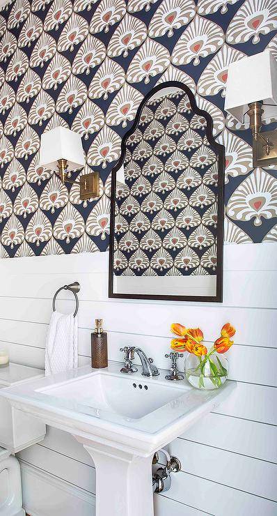 bold graphic wallpaper in bathroom with black arch mirror white wall sconces pedestal sink