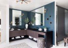 Brown and blue master bath features a L shaped dual washstand in brown veneer accented with a black quartz waterfall edge on a blue wall.
