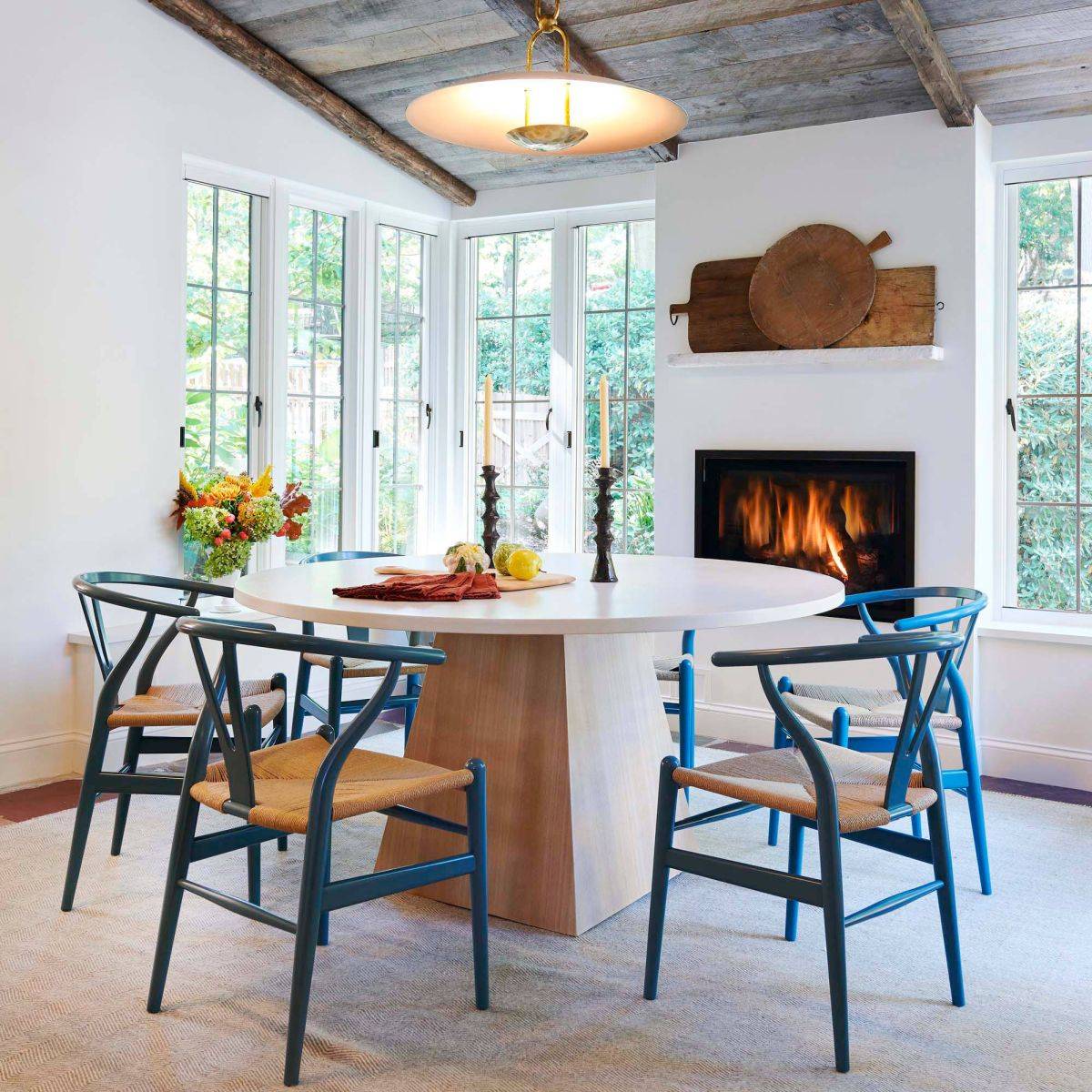 Classic-wishbone-chair-in-blue-adds-color-and-class-to-this-white-dining-room-with-fireplace-50287