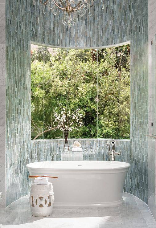 Contemporary master bathroom designed with a bow window bathtub nook tiled with blue glass and a polished nickel tub filler.