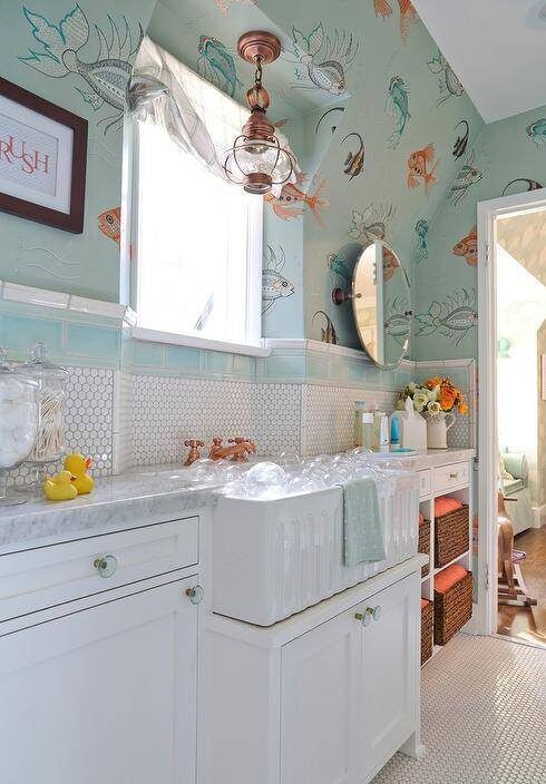 fish themed kids' bathroom with white washstand, white hex backsplash tiles lined with blue subway border tiles mounted beneath a window framed colorful turquoise fish wallpaper