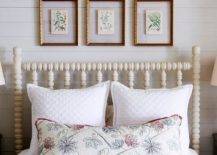 gold framed botanical prints hanging in a gallery wall above a white spindal bed