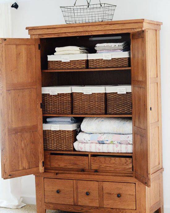 open brown cupboard full of towels and wicker baskets