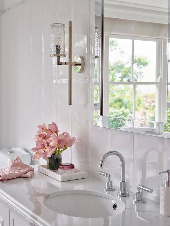 Bathroom features a chrome beveled mirror on a glossy white vertical plank wall over a marble tray on a marble look countertop.