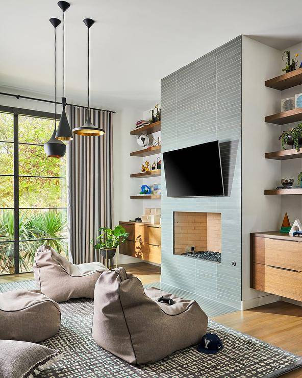 Gray modern bean bags sit in front of a gray tiled fireplace under a mounted TV.