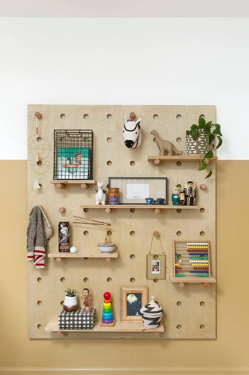 Boy nursery peg wall organizer on a mustard yellow nursery wall features vintage wood toys and fun accenting decor.