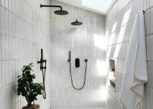 sloped ceiling walk in shower with skylight window black faucets hanging white towel