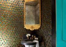 Turquoise door opens up to stunning tiny powder room featuring custom peacock feather wallpaper framing corner mirror, Georgian gold leaf mirror, over round corner sink.