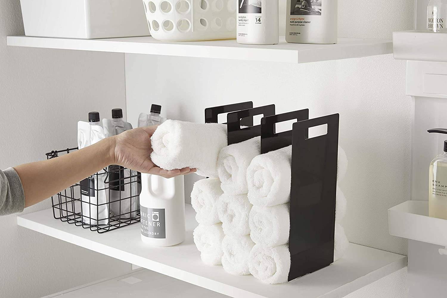 interlocking towel organizer with white towels on laundry room shelf next to shampoos and soap bottles