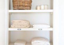 linen closet with white towels and sheets candles and a wicker basket