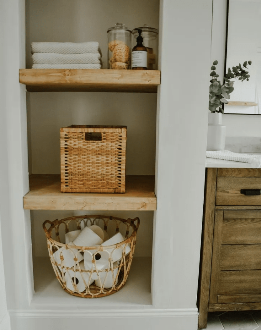 open bathroom closet with basket folded towels toilet paper glass apothecary jars